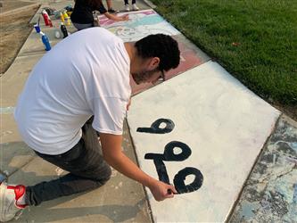 student painting sidewalk