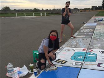 two students painting the sidewalk