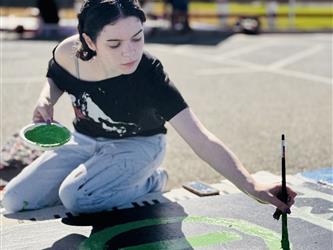 student painting on sidewalk