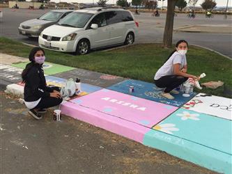 two students painting the sidewalk