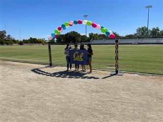 Students holding a Cal sign under an balloon arch